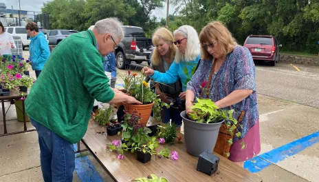 Senior citizens potting plants outside on a table