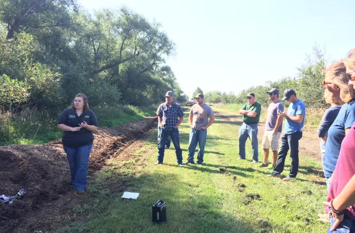 woman standing next to manure compost pile talking to a crowdabout
