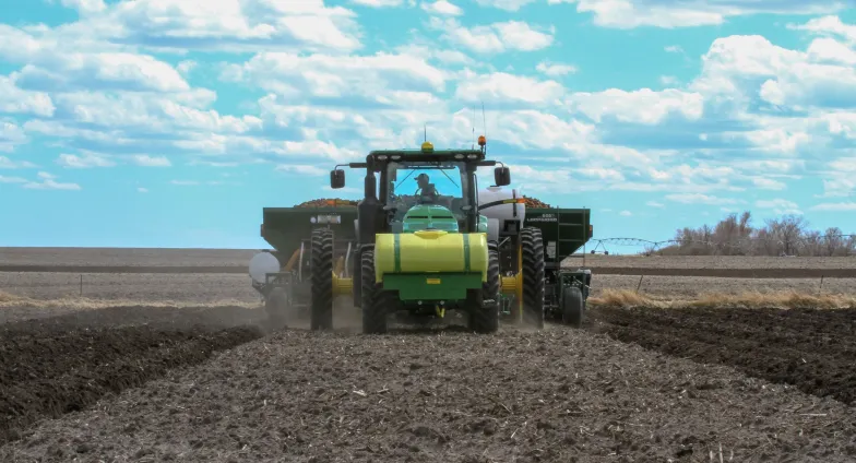 man in a green tractor working in a field