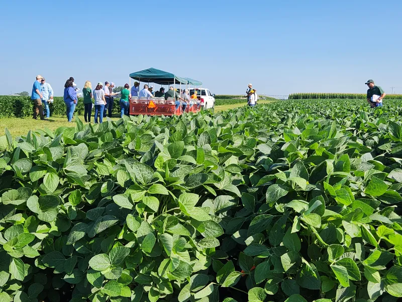 a group on a trailer in front of a healthy crop
