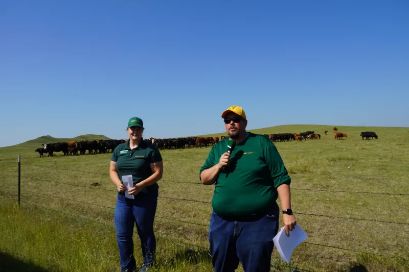 Two men speaking in front of a pasture