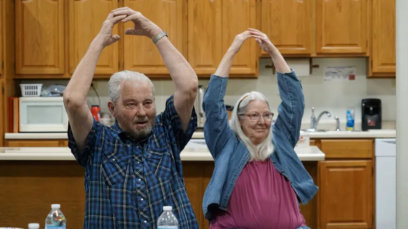 A man and a woman with arms above heads and fingers touching