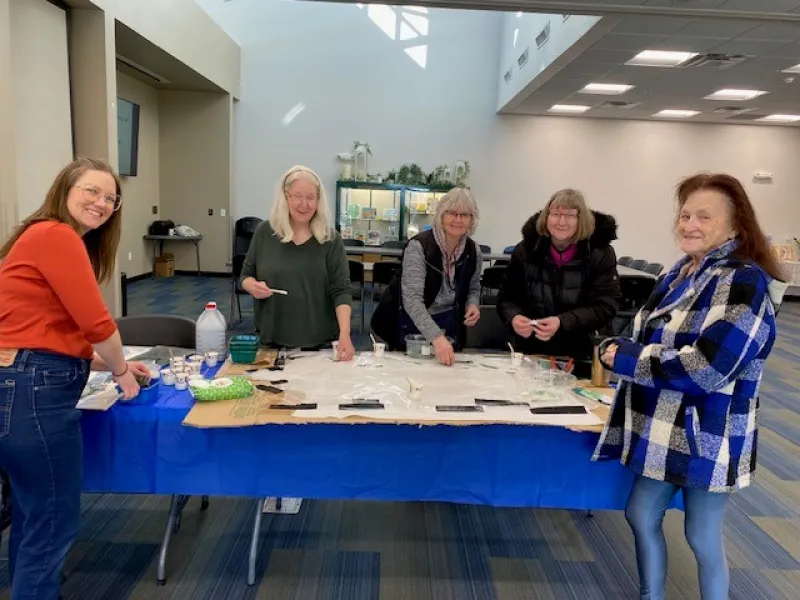 Women gluing mosaic pieces on a sign for the library 