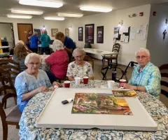 three senior citizens with their finished puzzle