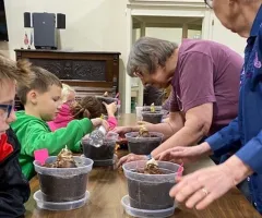 elderly women help children pot amaryllis plants 