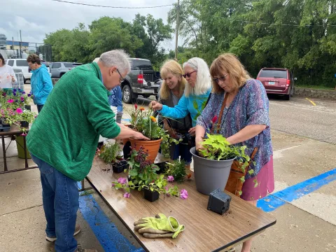 Senior citizens potting plants outside on a table