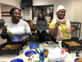 three women preparing food in electric skillets